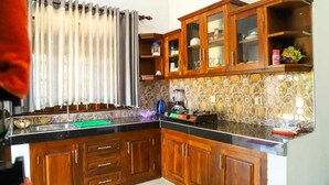 Una cocina con armarios de madera, encimera negra y salpicadero estampado.