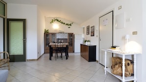 A modern kitchen with a dining area, white tiled flooring, and a white refrigerator. - Trilo Mina 4 in Gabicce Mare (Cattolica)