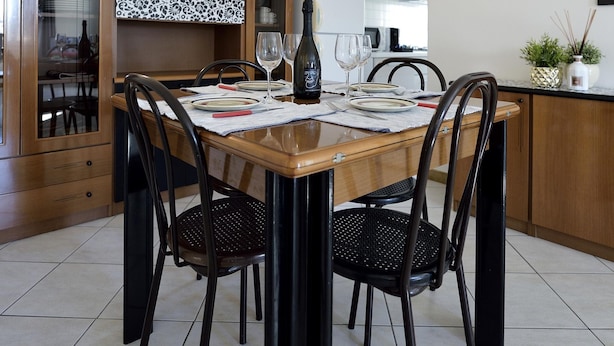 A dining area with a wooden table set for four, surrounded by black chairs. A bottle of wine and wine glasses are on the table. - Trilo Mina 4 in Gabicce Mare (Cattolica)