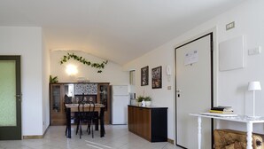 A compact living space with a dining area, kitchenette, and a small seating area with a sofa and a chair. - Trilo Mina 4 in Gabicce Mare (Cattolica)