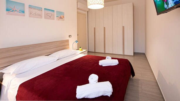 Ein Hotelzimmer mit einem großen Bett, einem an der Wand montierten Fernseher und einem Kleiderschrank.