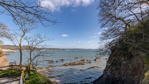 Un sentier côtier doté d’une rambarde en bois, bordé d’une côte rocheuse et offrant une vue dégagée sur la mer.