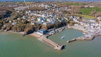 An aerial view of 5 Monkstone Court, featuring a coastal location with a marina, residential buildings, and a prominent waterfront.