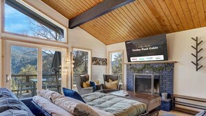 A cabin interior with a bed, seating area, fireplace, and a sign indicating availability of Netflix, Hulu, and Sling TV. - Timber Peak Cabin! Hot Tub,BBQ & Scenic Views! (Divide)
