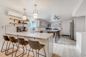 A modern kitchen with a central island, bar stools, and pendant lighting.