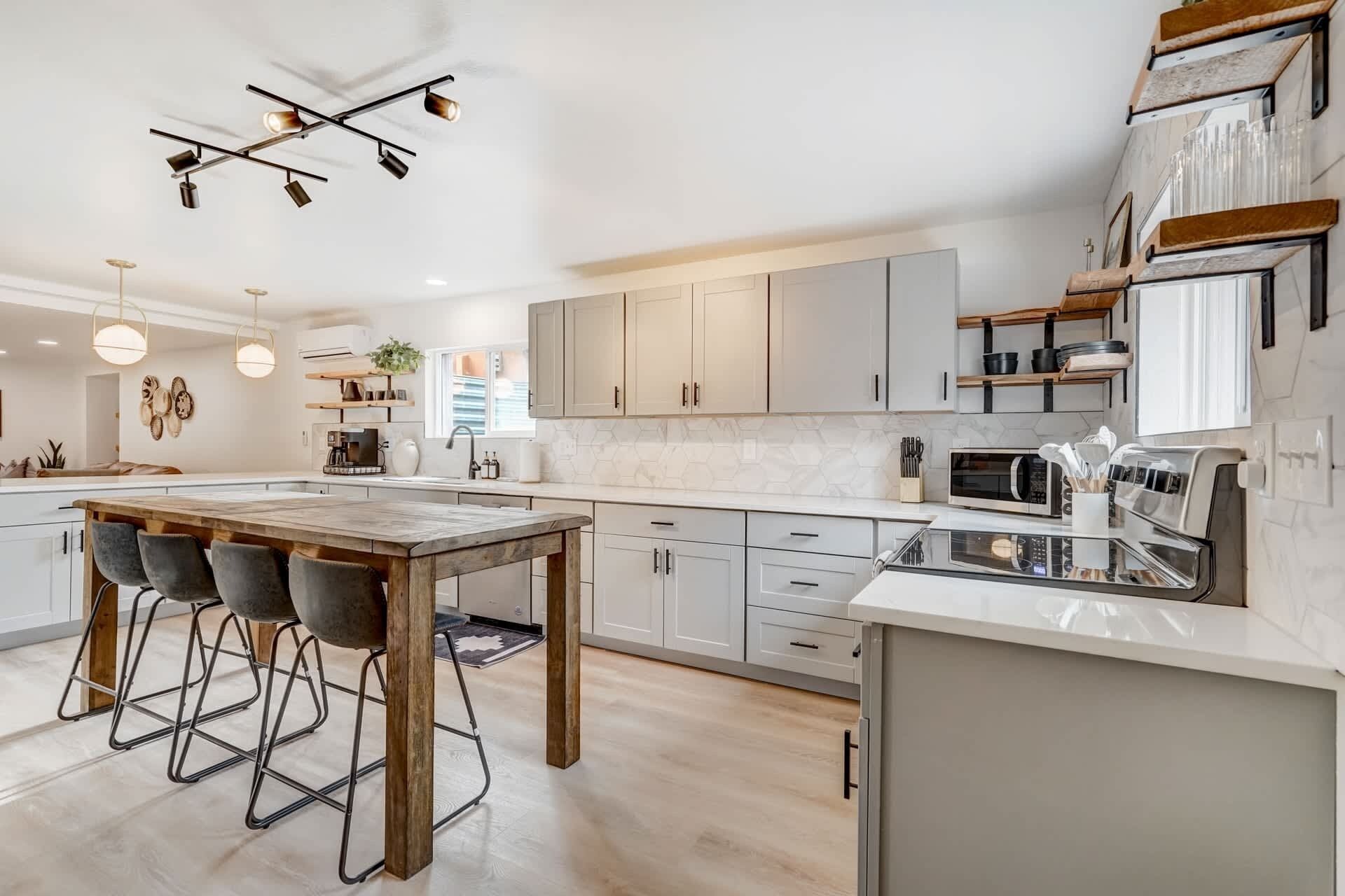 A modern kitchen with a central island, bar stools, and a dining area.