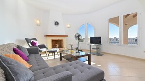 A modern living room with a grey sofa, a fireplace, a TV, and large windows with a city view. - Wonderful and comfortable villa  with private pool in Benitachell, Costa Blanca, Spain for 6 persons (Benitachell)