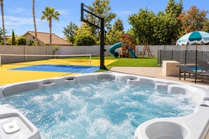 A hot tub with a basketball court and a slide in the background.