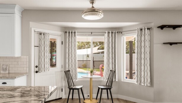 A corner kitchen with a marble countertop, two black chairs, and a gold bar stool. - Private Pickleball Court, Movie Room, & Hot Tub! (Scottsdale)