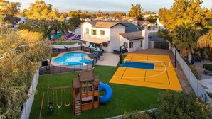 A residential property with a swimming pool, a basketball court, and a children's play area. - Private Pickleball Court, Movie Room, & Hot Tub! (Scottsdale)