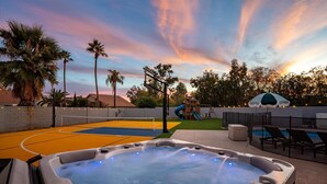 A hot tub with a control panel, a basketball court, a slide, and lounge chairs by a pool. - Private Pickleball Court, Movie Room, & Hot Tub! (Scottsdale)