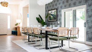 A dining area with a wooden table, green cushioned chairs, and a chandelier.