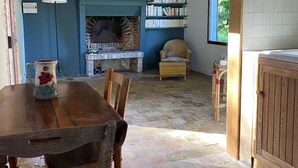 Ein gemütliches Zimmer mit Kamin, Bücherregal und Essecke mit Holztisch und Stühlen.
