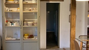 Eine Küche mit Holzboden, einem Esstisch mit Stühlen und einem Schrank mit Geschirr.