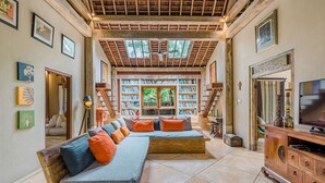 A spacious living room with a large sectional sofa, a wooden entertainment center, and a bookshelf filled with books.