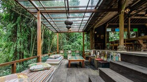A wooden deck with a glass ceiling, surrounded by lush greenery.