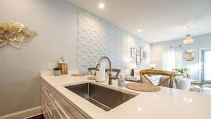 Une cuisine moderne dotée d’un grand îlot central, d’un évier en acier inoxydable et de chaises en bois.