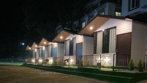 A row of single-story cabins with individual porches, each with a door and a small window. - The Bluewind Resort (Dehradun)
