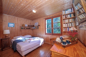 A wooden cabin with two beds, a bookshelf, a window with a view, and a table with cups and a teapot. - Chalet L’eau vive, Le Tour (Argentière), France (Le Tour (Argentière))