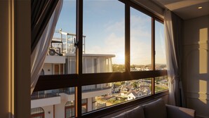 A room with a large window, a sofa, and a view of a building with balconies. - Cat Tuong Hotel (Lam Vien - Da Lat)