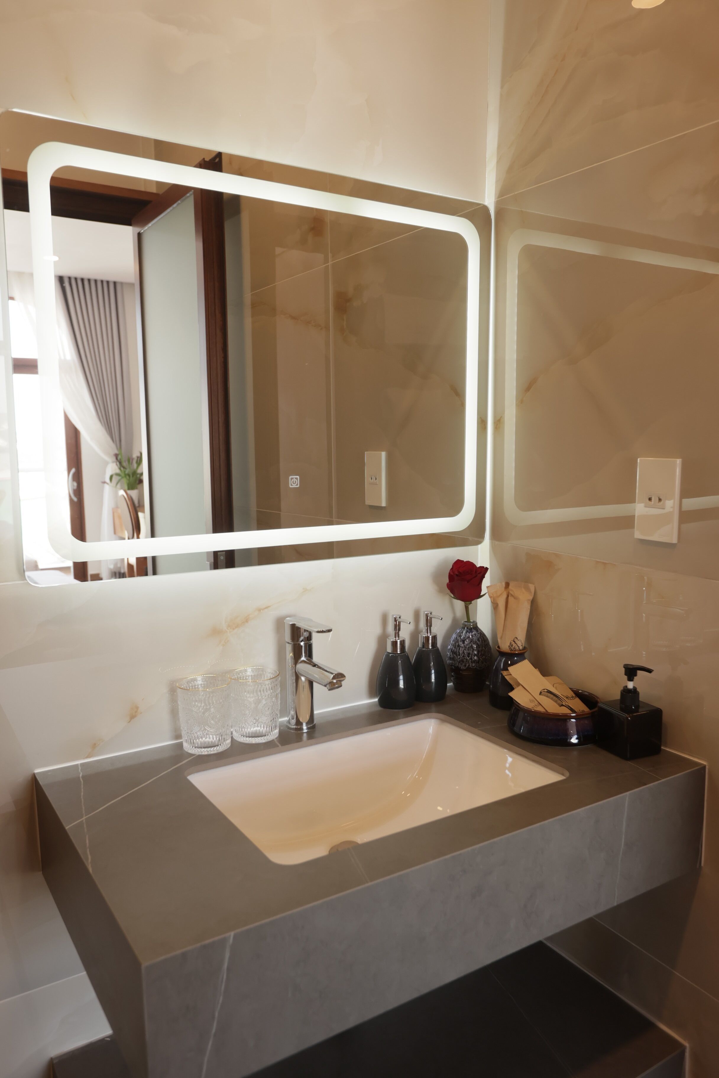 A bathroom with a large mirror, a sink, and a vanity area.
