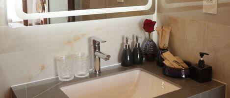 A bathroom with a large mirror, a sink, and a vanity area.