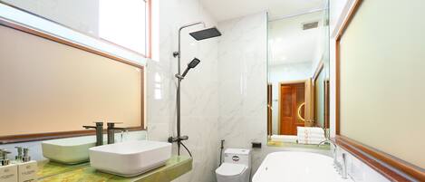 Un bagno moderno con una vasca da bagno ampia, un soffione doccia e un water.
