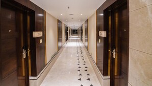 A long, narrow hallway with doors marked with numbers, leading to rooms. - UVA MANISH (Kundapur)