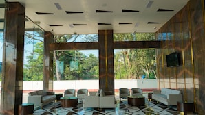 A lobby with a checkered floor, seating area, and large windows with a view of greenery. - UVA MANISH (Kundapur)