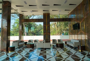 A lobby with a checkered floor, seating area, and large windows with a view of greenery.