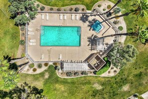 Eine Vogelperspektive eines Poolbereichs mit einem großen rechteckigen Pool, mehreren Liegestühlen und einem kleineren Pool.