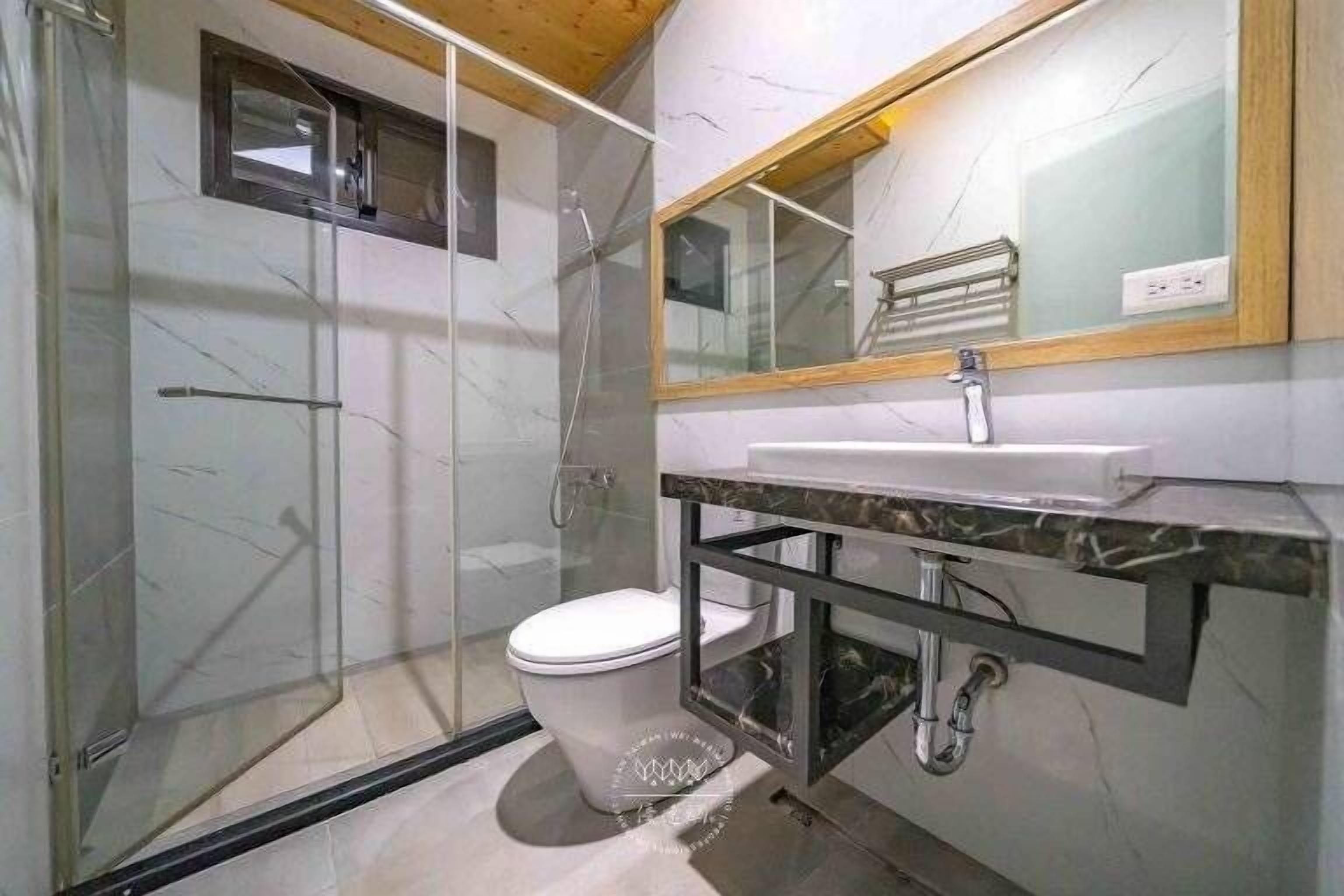 A modern bathroom with a glass-enclosed shower, a white toilet, and a marble countertop with a sink.