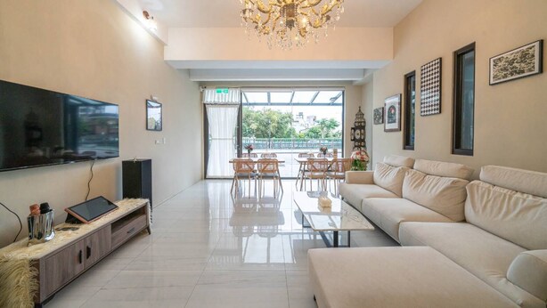 A modern living room with a flat-screen TV, a sofa, a coffee table, and a chandelier. - Near River Homestay (Ji'an)