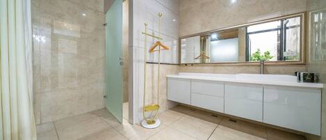 Un baño moderno con un espejo grande, un tocador blanco y un box de ducha de vidrio.