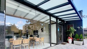 A modern outdoor seating area with glass walls, wicker chairs, and a tiled floor. - Near River Homestay (Ji'an)