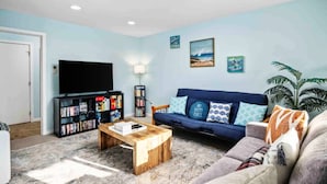 A living room with a TV, bookshelf, sofa, coffee table, and a plant. - Fantastic Rockaway Family Escape – Close to Beach with BBQ (Rockaway Beach)