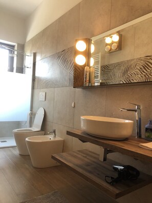 Een moderne badkamer met een toiletbril, een wastafel en een spiegel met verlichting.