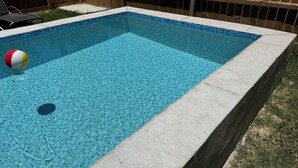 Ein rechteckiger Swimmingpool mit klarem, blauen Wasser und einer gefliesten Kante.