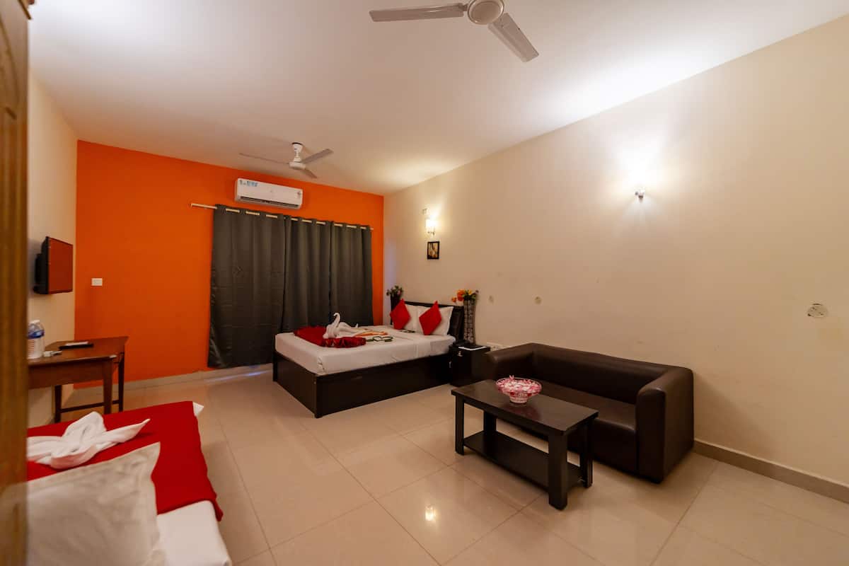 Habitación de hotel con cama, sofá, una mesita y ventilador de techo.
