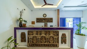 A reception area with a ceiling fan, a clock, a decorative wall panel, and a reception desk. - Starlite Hotels (Vanur)