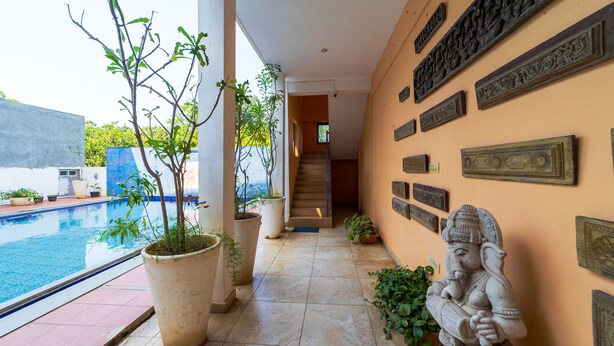 A poolside corridor with potted plants, a statue, and decorative wall plaques. - Starlite Hotels (Vanur)