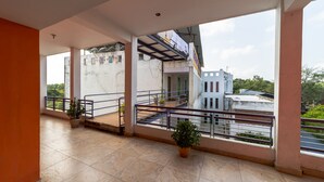 A spacious balcony with tiled flooring, potted plants, and a view of surrounding buildings. - Starlite Hotels (Vanur)
