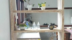 Une étagère en bois rustique, composée de trois niveaux, sur lesquels sont disposés divers objets décoratifs et plantes.