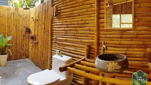 A bamboo-walled bathroom with a toilet, shower, and a decorative bowl. - Hide Away Homestay (Phu Khuong)