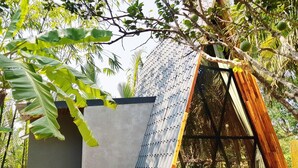 A modern building with a corrugated metal roof, surrounded by lush greenery and trees. - Hide Away Homestay (Phu Khuong)