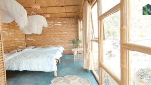 A room with a bed, a small table with a plant, and large windows. - Hide Away Homestay (Phu Khuong)