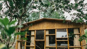 A bamboo structure with large windows, surrounded by trees. - Hide Away Homestay (Phu Khuong)