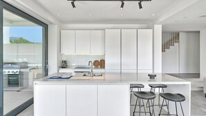A modern kitchen with a large island, bar stools, and a view of the outdoors.