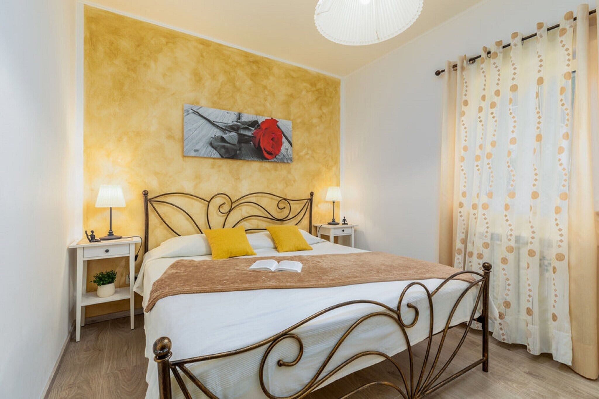 Ein ordentlich eingerichtetes Schlafzimmer mit einem Bett, zwei Nachttischen, einem Wandbild und einem Vorhang mit Punkten.