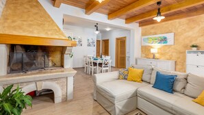 A cozy living room with a fireplace, a dining area, and a sofa with cushions.